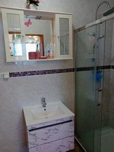 ein Bad mit einem Waschbecken und einer Glasdusche in der Unterkunft Casa di Vacanza in Porto Tolle