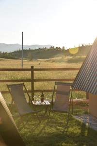 twee stoelen en een tafel voor een hek bij Cottages Big bear in Žabljak