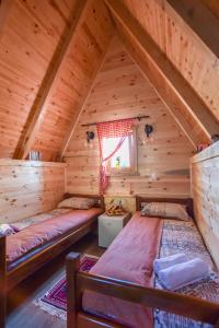 two beds in a log cabin with a window at Cottages Big bear in Žabljak