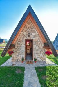 een klein stenen gebouw met een deur in een veld bij Cottages Big bear in Žabljak