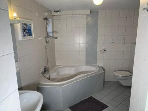 a white bathroom with a tub and a toilet at Edu Home Bremen in Bremen