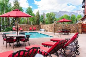 eine Terrasse mit Tischen und Sonnenschirmen neben einem Pool in der Unterkunft Bear Creek Lodge 207B by Alpine Lodging Telluride in Telluride