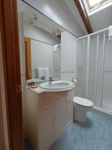 een badkamer met een wastafel, een toilet en een spiegel bij Casa Guadalupe in Llanes