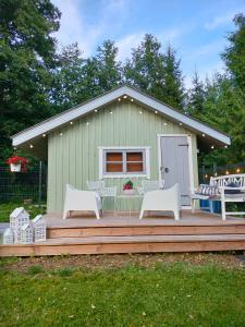 a green building with a deck with chairs and a house at Metsatuule puhkeküla in Hiiumaa