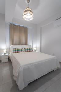 a white bedroom with a large white bed and a chandelier at Isida - cozy sea walk lodge with private garden in Nea Makri