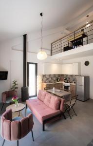 a living room with a pink couch and a kitchen at Isida - cozy sea walk lodge with private garden in Nea Makri