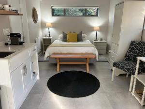 ein Schlafzimmer mit einem Bett und einem Tisch sowie eine Küche in der Unterkunft The Wood Owl Nature's Valley in Natureʼs Valley