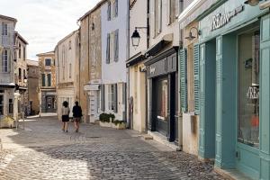 dos personas caminando por una calle adoquinada en La Martinoise Studio, en Saint-Martin-de-Ré