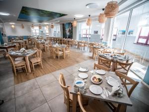 un comedor con mesas, sillas y ventanas en Sanatorium Mewa, en Kołobrzeg