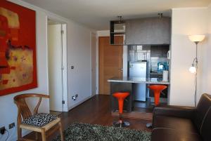 a living room with a kitchen with orange stools at Apartamento Virgilio Arias in Antofagasta