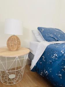 Bett mit blauer Bettdecke und Beistelltisch in der Unterkunft Stunning 2 bedroom Guesthouse in Tamahere