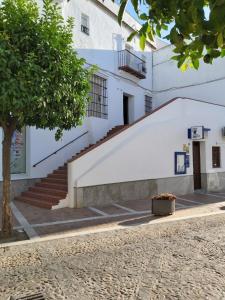 un edificio blanco con escaleras y un árbol en Casa Abuelo Miguel, en Arcos de la Frontera