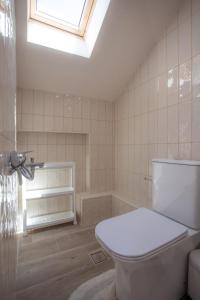 La salle de bains est pourvue de toilettes blanches et d'une lucarne. dans l'établissement Isida - cozy sea walk lodge with private garden, à Nea Makri