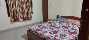 a bedroom with a bed with a floral comforter at Adithya Residency Guruvayur in Guruvāyūr