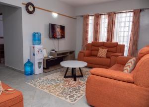 uma sala de estar com dois sofás e uma mesa em Havan Furnished Apartments- Hyrax Hill em Nakuru