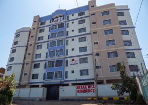 um edifício alto com um sinal em frente em Havan Furnished Apartments- Hyrax Hill em Nakuru