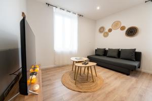 een woonkamer met een zwarte bank en een tafel bij KASA ZEN - Climatisation - Tout équipé - Stationnement gratuit in Saint-Chamond