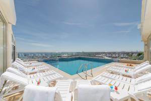 une piscine avec des chaises blanches et une piscine dans l'établissement Piya Sport Hotel, à Istanbul