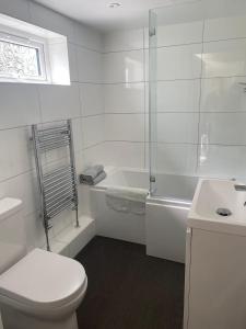 a white bathroom with a toilet and a sink at Primrose Steps in Goodrington