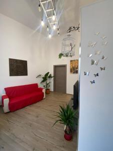 un soggiorno con divano rosso e uccelli sul muro di B&B Leoncavallo a Grottaglie