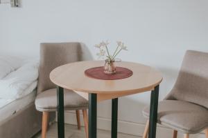 una mesa redonda con 2 sillas y un jarrón con flores en Apartmani Terase, en Konjska Reka