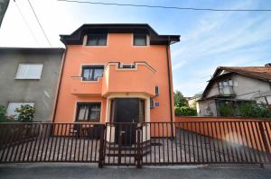 ein orangenes Haus mit einem Zaun davor in der Unterkunft Apartment Ana in Zagreb
