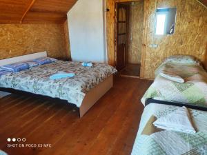 2 łóżka w pokoju z drewnianą podłogą w obiekcie Guest House Doktor Eismann w mieście Chychkan