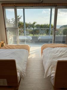 two beds in a room with a large window at Kith villa Kodomari 1 - Vacation STAY 14454 in Amami