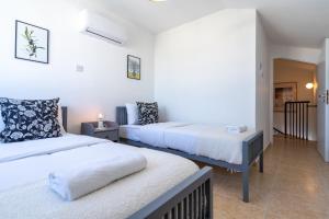 2 camas en una habitación con paredes blancas en Chloris 3- Bedroom Apartment W/Pool in Larnaca, en Lárnaca
