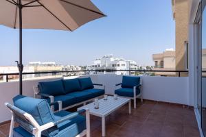 a balcony with chairs and a table and an umbrella at Chloris 3- Bedroom Apartment W/Pool in Larnaca in Larnaca