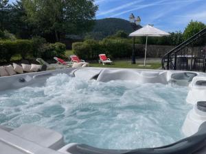 une baignoire jacuzzi remplie d'eau dans un jardin dans l'établissement La maison des douceurs, à Bussang