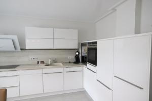 a white kitchen with white cabinets and a sink at Monteurwohnung Saarlouis, Ferienhaus, WLAN, Parkplatz in Saarlouis