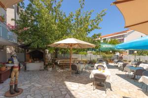 a patio with tables and chairs and umbrellas at Pansion Pirat in Petrcane