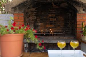 twee wijnglazen zittend op een tafel voor een bakstenen oven bij Pansion Pirat in Petrcane