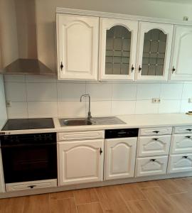 a kitchen with white cabinets and a sink at Haus Waldblick in Liebenwalde