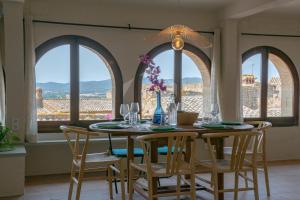 a dining room with a table and chairs and windows at PALS - Maison médiévale tout confort in Pals +24 photos