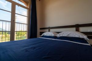um quarto com uma cama azul e uma grande janela em Corte Volpe Home em Lucca
