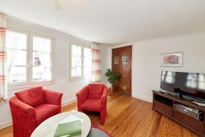 ein Wohnzimmer mit 2 roten Stühlen und einem TV in der Unterkunft Ferienwohnung Altstadt in Bernkastel-Kues