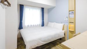 - un lit blanc dans une chambre avec fenêtre dans l'établissement Toyoko Inn Futamatagawa-eki Kita-guchi, à Yokohama