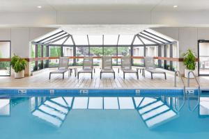 a pool in a hotel with chairs and a table at Courtyard Rochester Brighton in Rochester