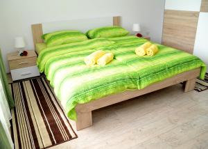 Un dormitorio con una cama verde con almohadas amarillas en Apartments Žugec, en Selište Drežničko