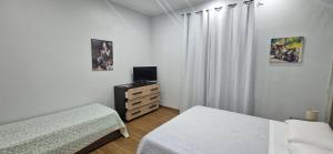 ヴィアグランデにあるB&B Mongibelloのベッドルーム1室(ベッド2台、テレビ、ドレッサー付)