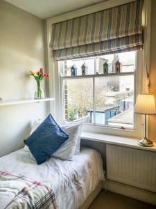a bedroom with a window with a blue pillow on a bed at Cliff Cottage with private garden - Broadstairs in Kent