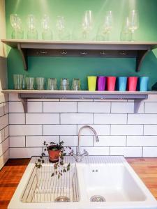 a kitchen with a sink and a shelf with glasses at Cliff Cottage with private garden - Broadstairs in Kent