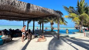un grupo de personas sentadas en la playa cerca del agua en NDAME Paje Hotel, en Paje