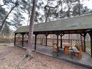 einen hölzernen Pavillon mit einer Bank und einem Baum in der Unterkunft Wydmy Helskie in Hel