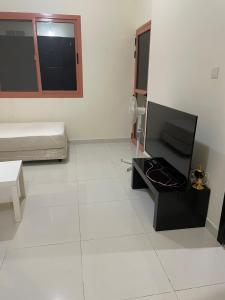 a living room with a television and a white floor at Najm home in Ajman 