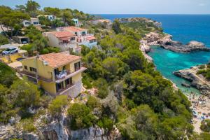 a house on a cliff next to a beach at Ses Savines Beach cala Llombards in Santanyi