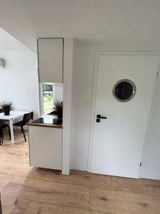 a white kitchen with a door and a table at Leśny Staw Stodoła in Gilwa