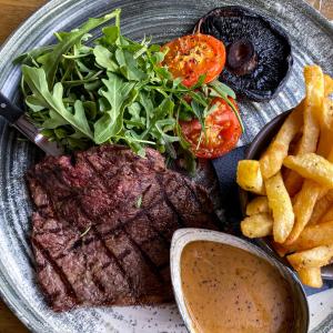 a plate with a steak and french fries and a salad at The Kings Head Inn, home of The Acle Steak in Acle